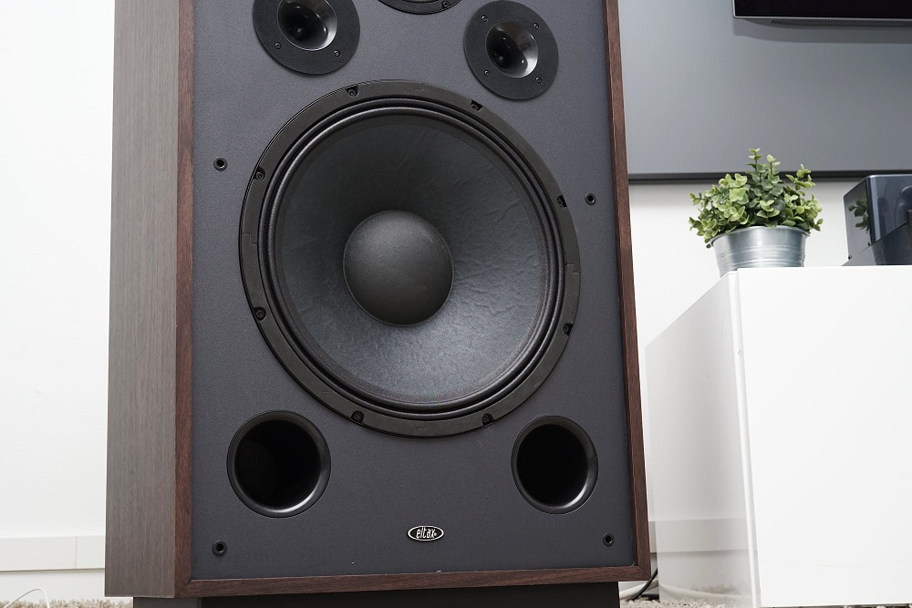 En golvhögtalare i valnöt med svart front, stor bas- och diskantelement.