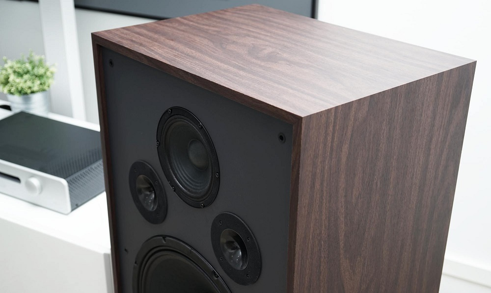 En golvhögtalare med en valnötträsyta och svarta element.