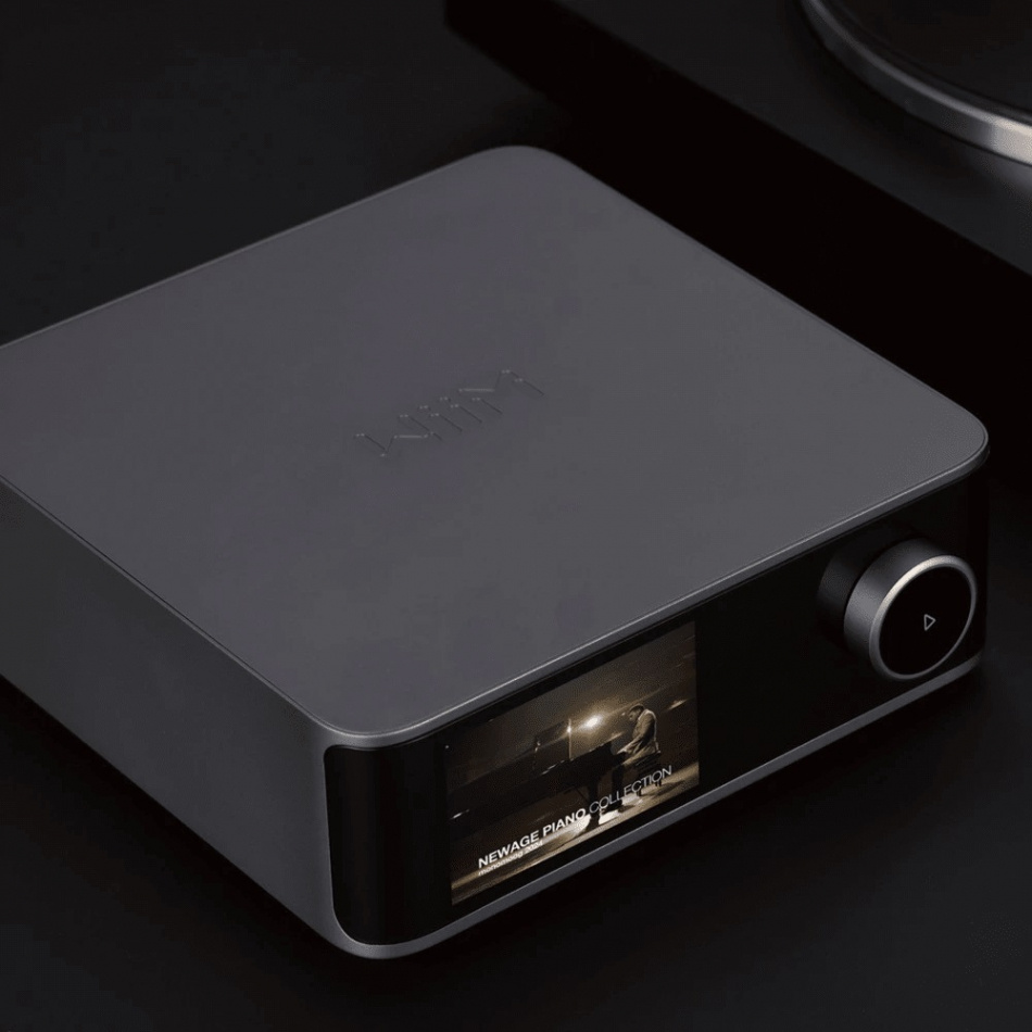 En mörkgrå nätverksspelare med pekskärm och volymknapp.