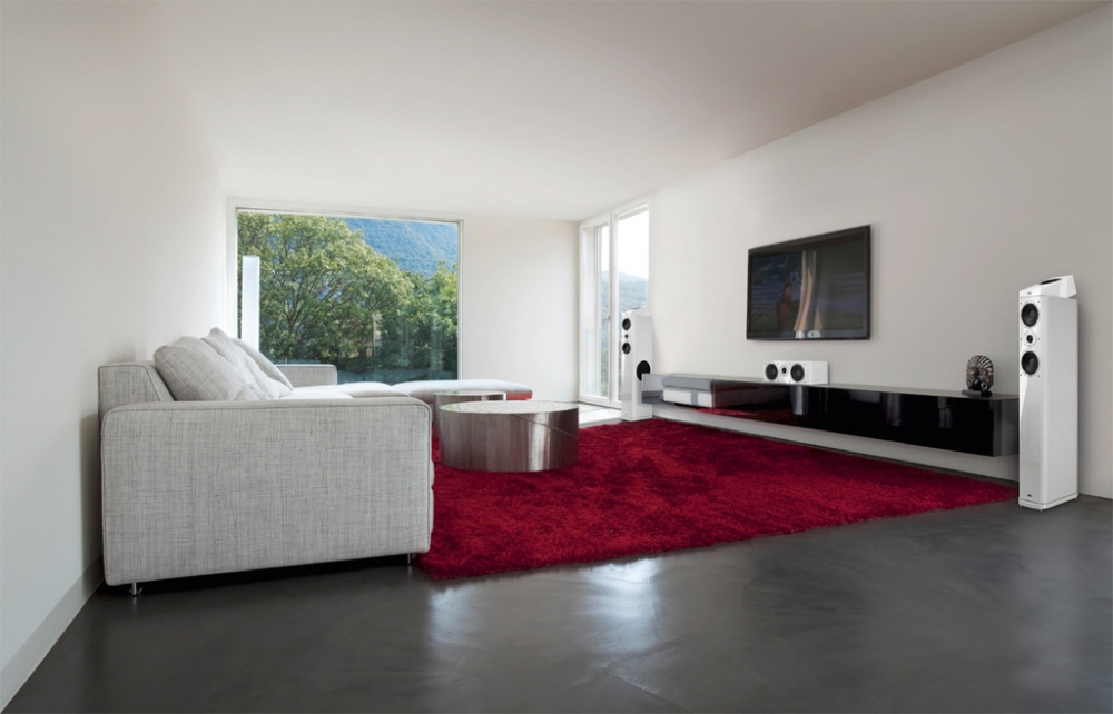 Ett modernt rum med vit inredning och Heco AM200 högtalare på vardera sidan om en TV.