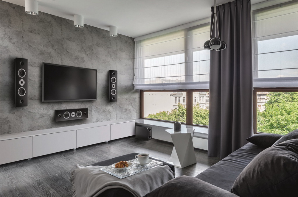 Ett modernt vardagsrum med TV, avlånga högtalare och stilren inredning.