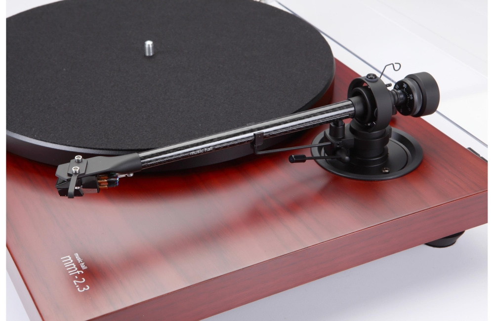 En skivspelare i ädelträ med tonarm och matta.