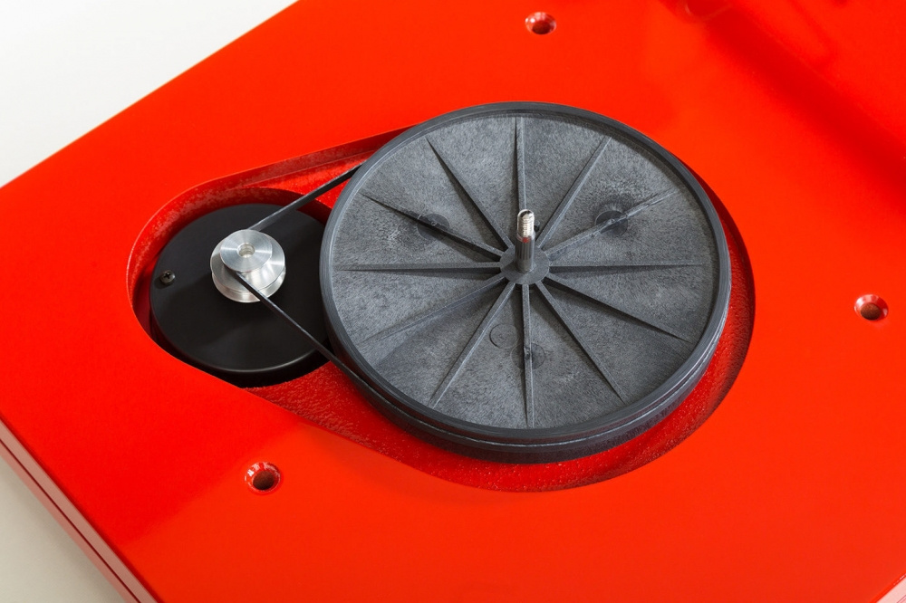 En röd skivspelare med gummiskiva och remdrivning.