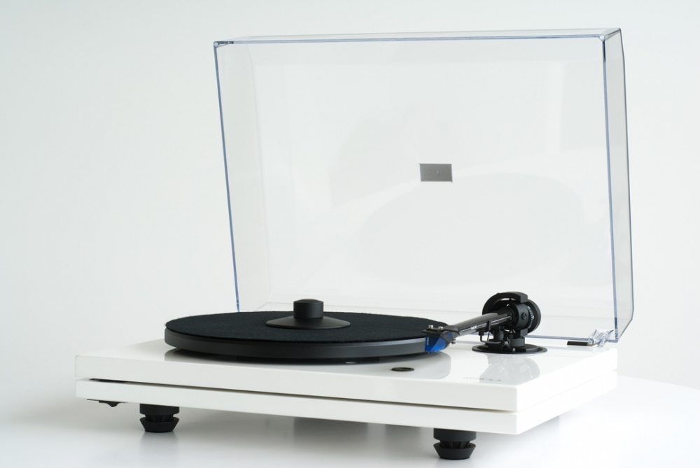 En vit skivspelare med genomskinligt lock och svart skivtallrik.