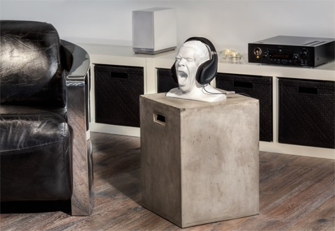 Ett hörlursställ i form av ett ansikte som skriker, placerat på en betongblock.