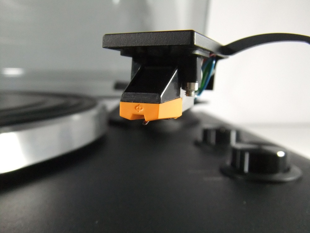 En svart och orange skivspelarnål monterad på en tonarm.