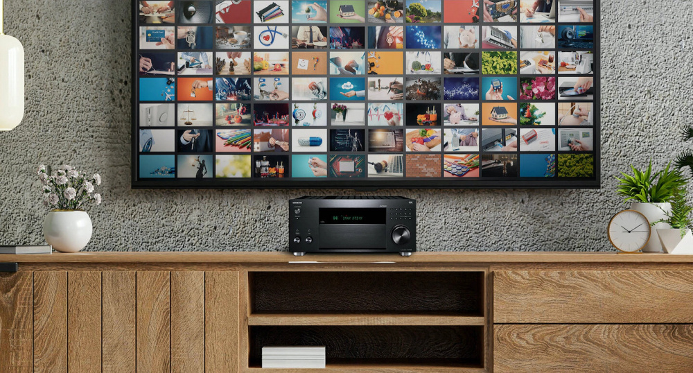 En svart förstärkare framför en vägg med många bilder.