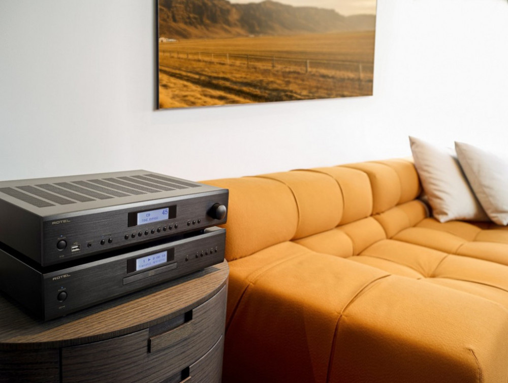 CD-spelare och förstärkare i svart på ett bord vid en orange soffa.