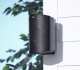 Polk Audio Atrium 4 utomhushögtalare, svart Svart utomhushögtalare monterad på vägg med gröna löv i bakgrunden.