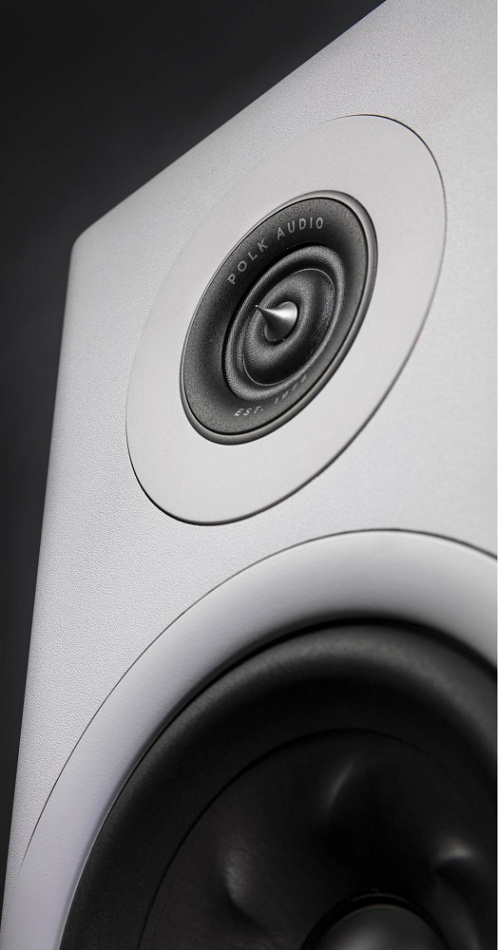 Vitt hörn med Polk Audio Reserve R600 högtalare och en ljus kon i fokus.