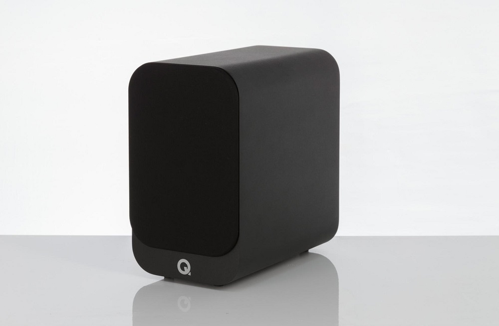 En svart, kompakt stativhögtalare med rundade hörn.