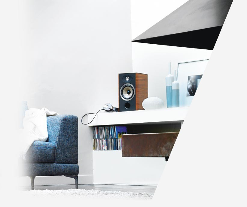 En stilren hörnvy med Focal Aria 906 högtalare och en blå soffa.