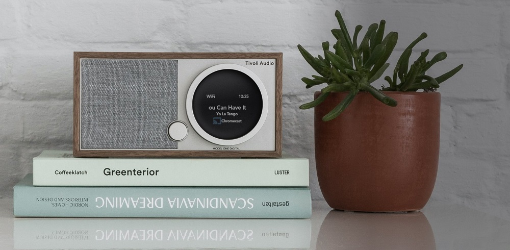 Internetradio i valnöt med skärm och högtalare, placerad på böcker och nära en växt.