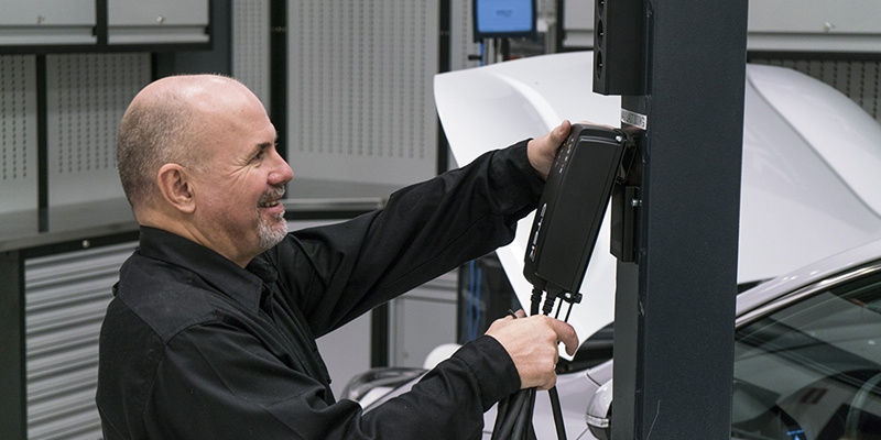 En man kopplar in en batteriladdare i en verkstad.