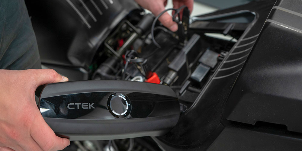 En person ansluter en CTEK CS One EU batteriladdare till en motorcykel.