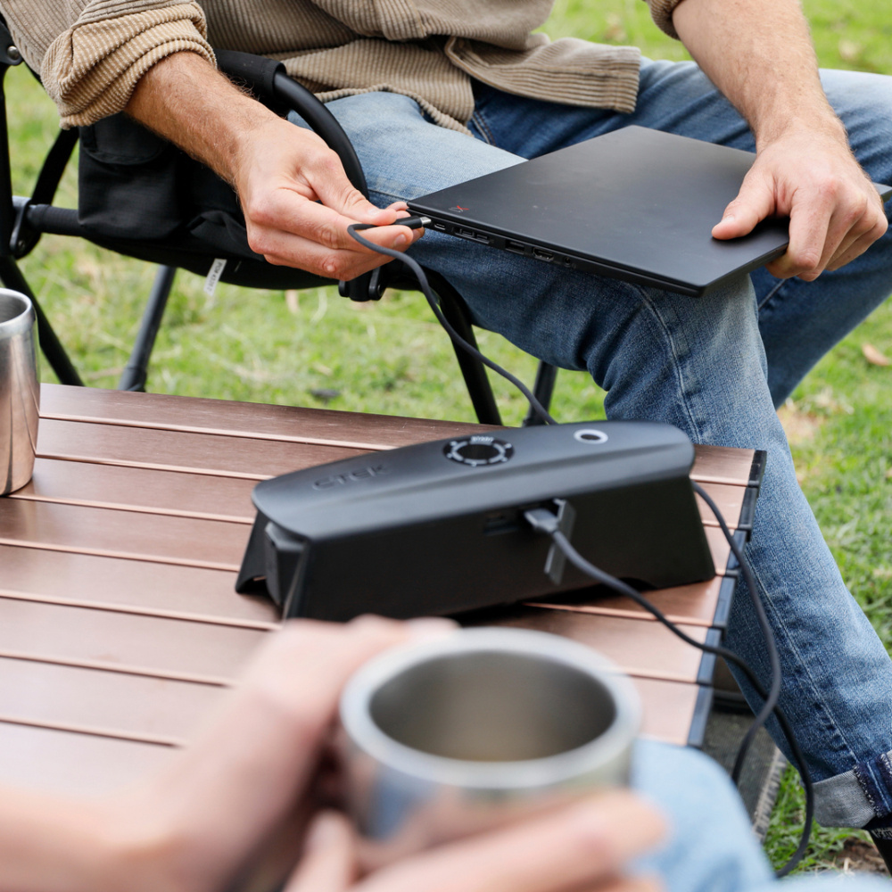 Portabel batteriladdare kopplad till en laptop utomhus.