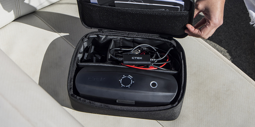 En svart förvaringsväska med kablar och en enhet inuti.