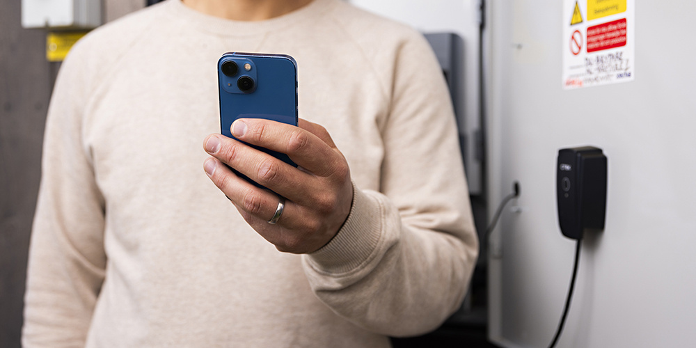 En person håller i en smartphone framför en enhet.