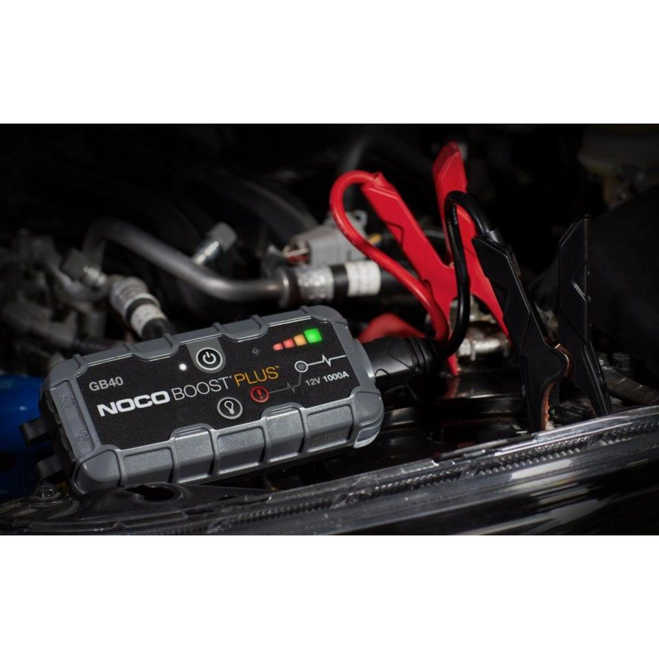 Ett startbooster kopplat till en bilmotor med klämmor.