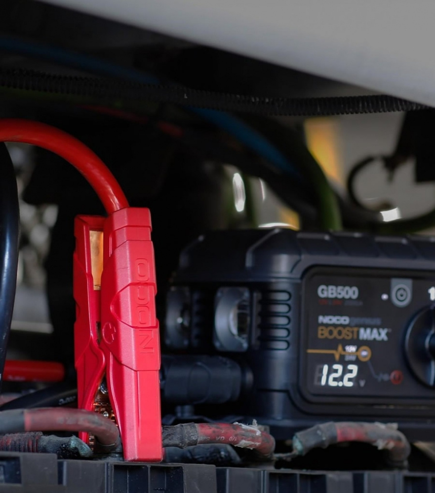 Röda batteriklämmor anslutna till en NOCO Boost Max GB500-enhet.