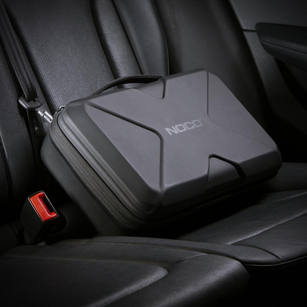 En svart förvaringsväska med NOCO-logga som ligger i en bils säte.