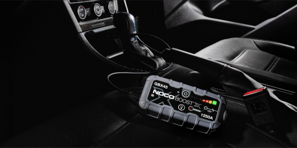 Ett startbooster ligger på en bils säte, med knappar och laddningsindikatorer.