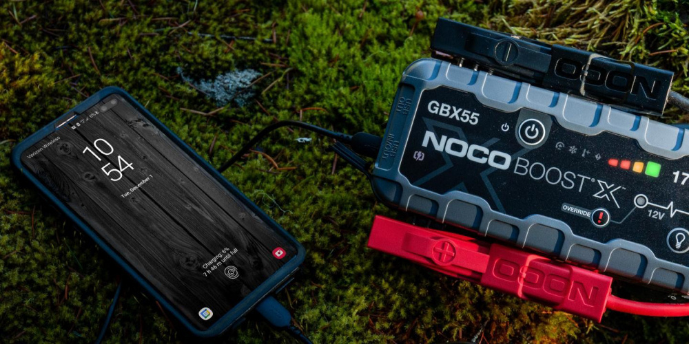 En NOCO Boost X GBX55 startbooster ansluten till en mobiltelefon.