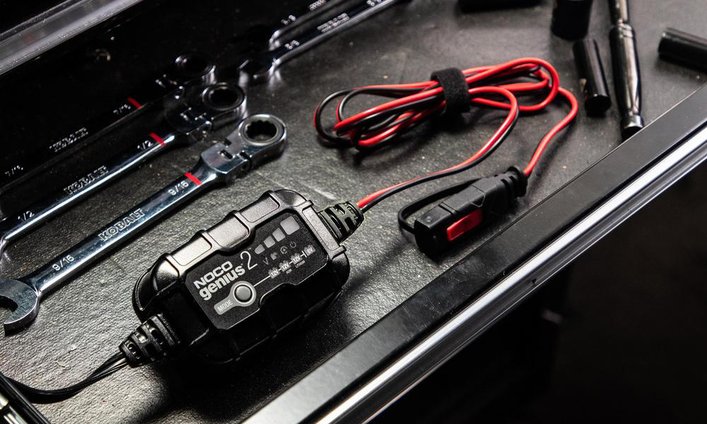 En batteriladdare med kabel och verktyg på en arbetsbänk.