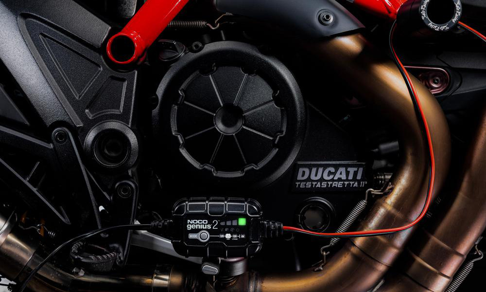Batteriladdare ansluten till en motorcykelmotor med Ducati-logotyp.