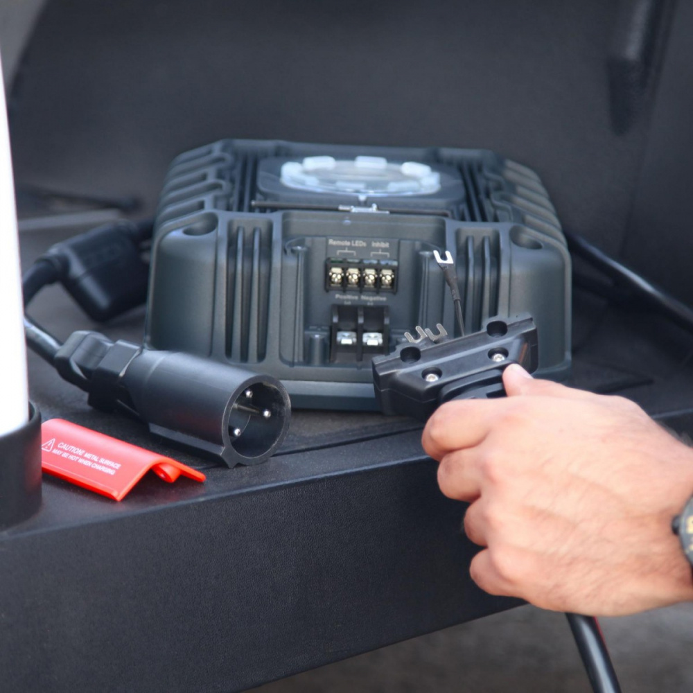 En person kopplar en kontakt till en enhet i en golfbil.