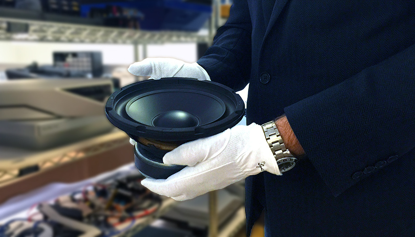 En person håller en högtalare i handen med handskar på.