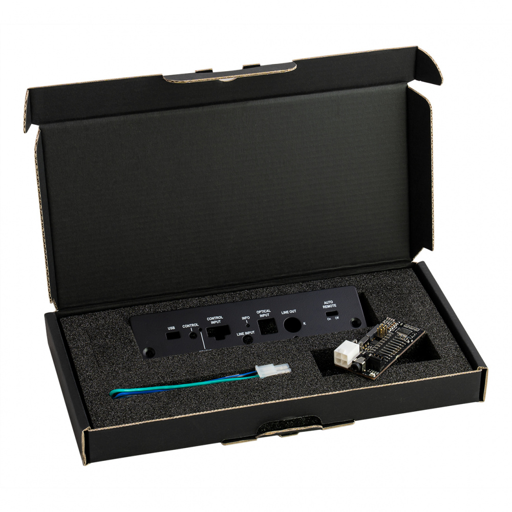 En öppen låda med en analog adapter och tillbehör för ljudsystem.