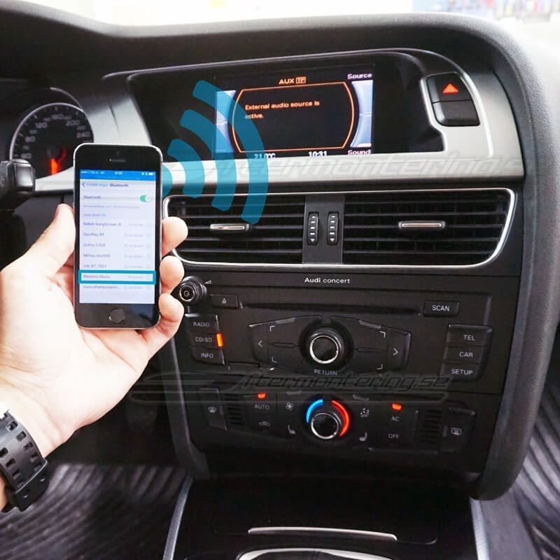 En hand håller en telefon vid en bils radio med Bluetooth-adapter.