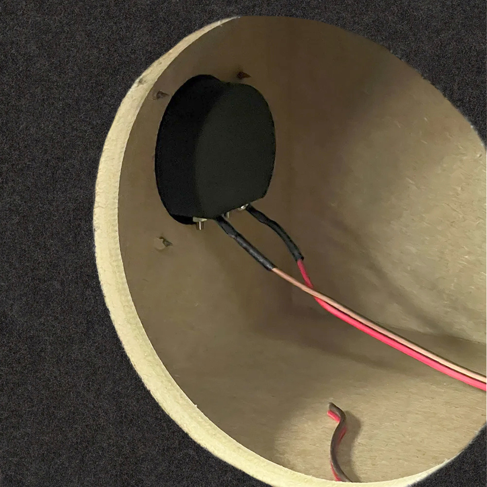 Ett hölje för en baslåda med anslutningar och kabeldragning inuti.