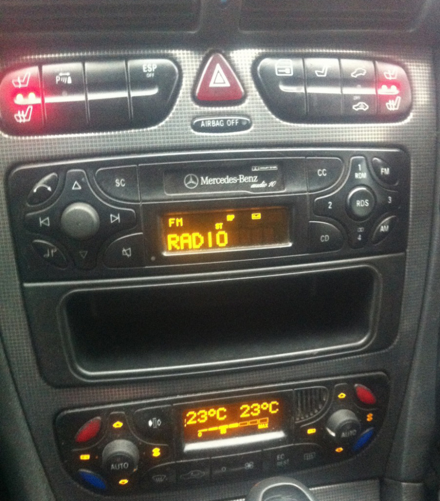 En bilradio med knappar och display, samt temperaturkontroller.