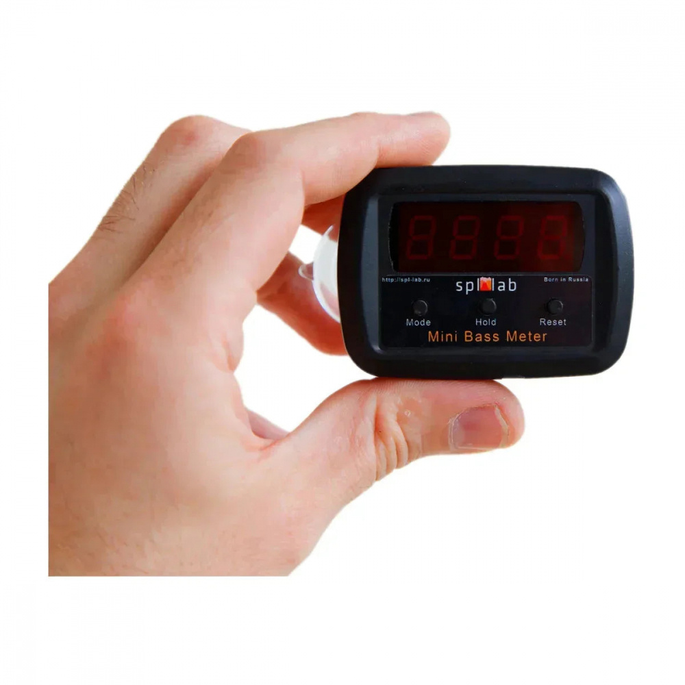 En hand håller en digital dB-mätare med röd display för ljudnivåmätning.