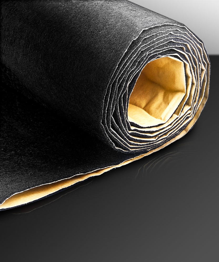 En svart högtalarmatta rullad med klisterbaksida.