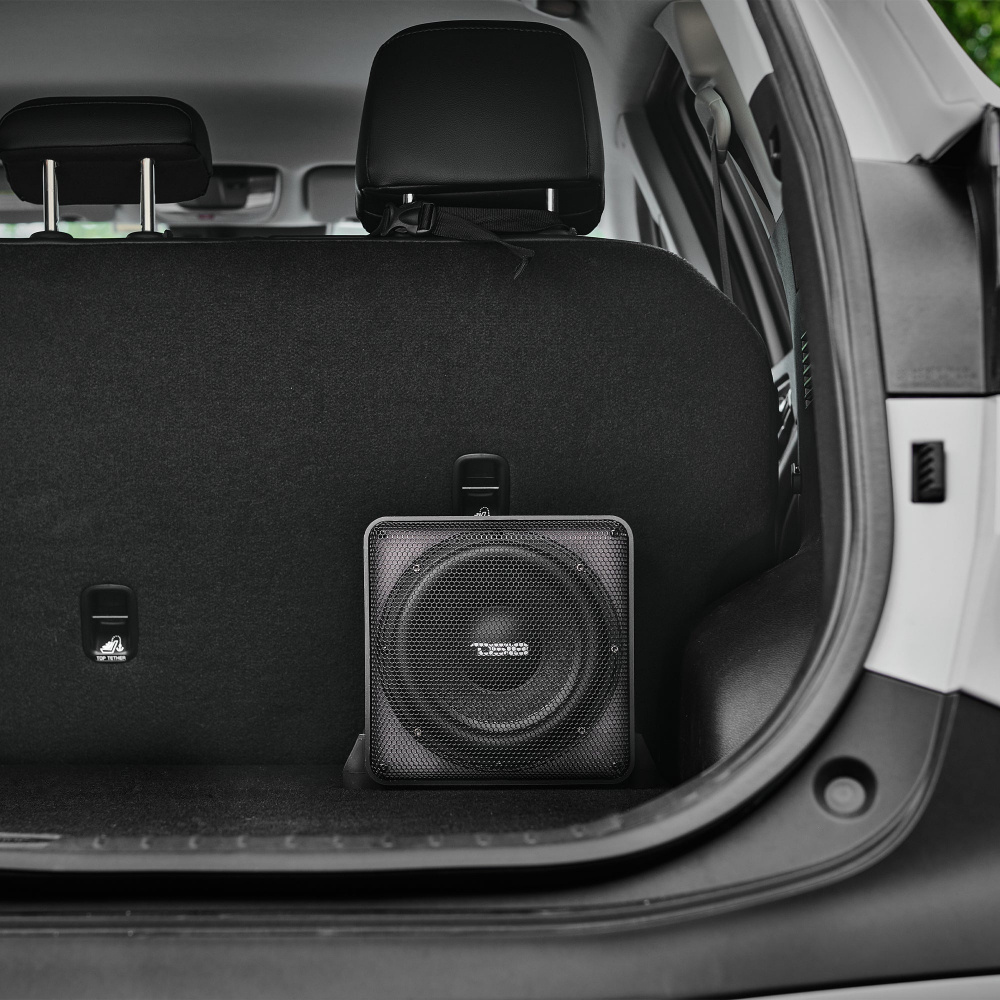 En aktiv 8-tums subwoofer står i bagageutrymmet på en bil.
