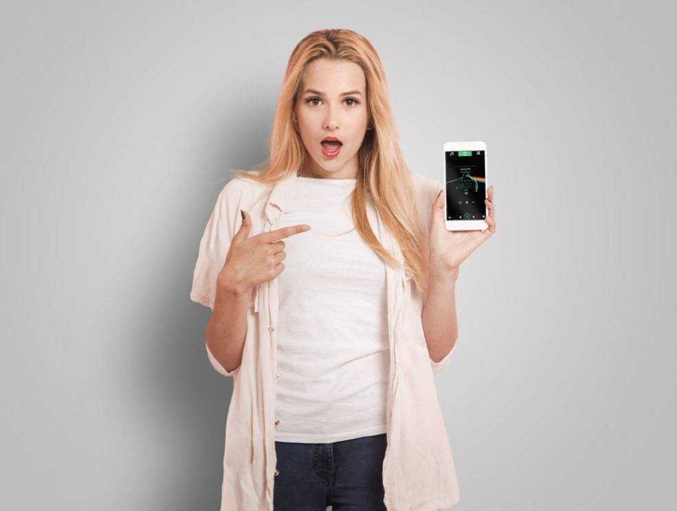 En kvinna pekar på en telefon som visar en ljudapp.