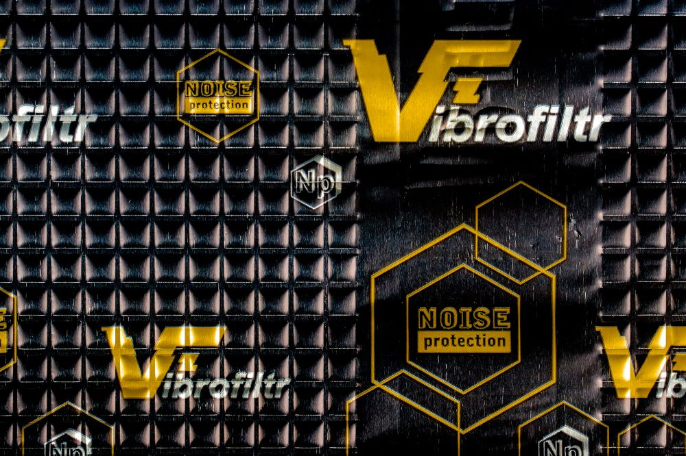 Svart dämpmatta med gul text och mönster för ljudskydd.