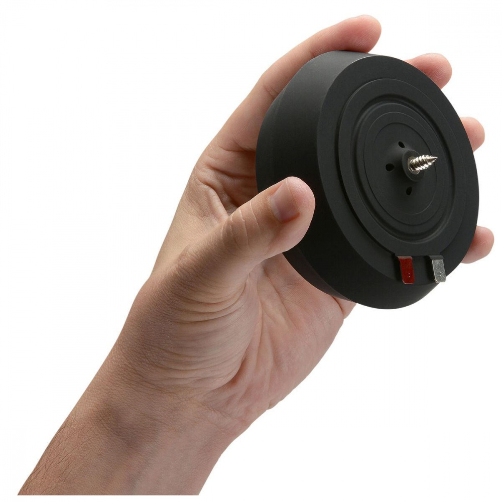 En hand håller en svart, rund vattentät exciter för ljudåtergivning.