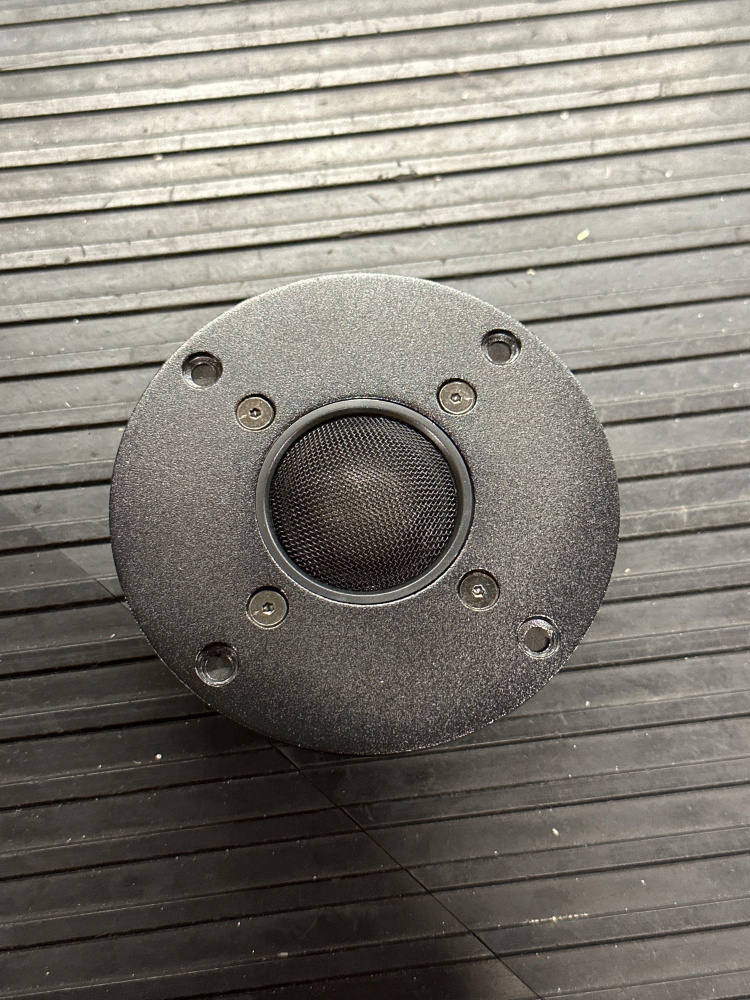 En rund högtalardrivare med svart hölje och nätfilter.