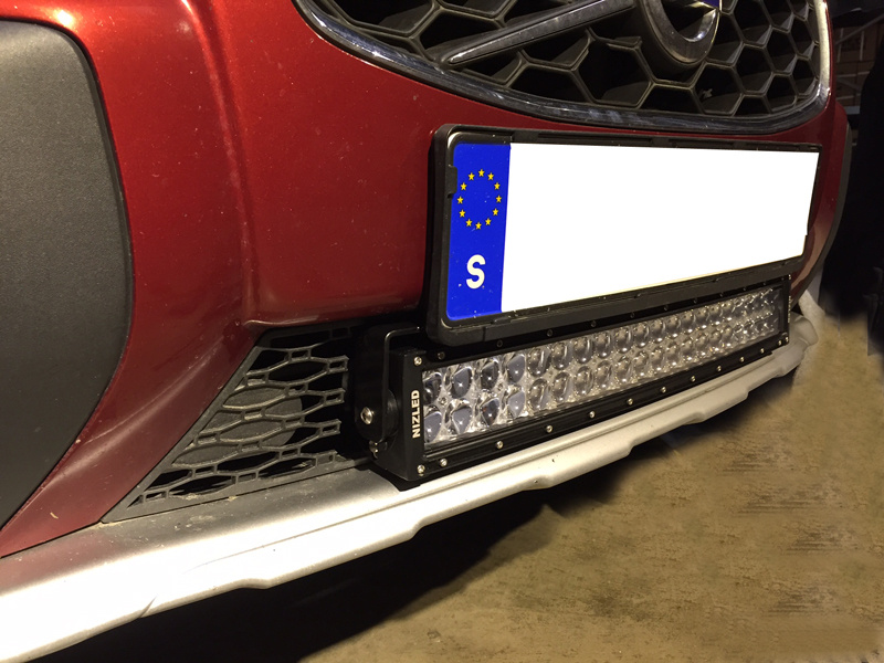 Nummerplåtfäste med LED-lampor under en registreringsskylt på bil.