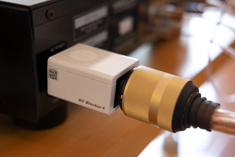 En liten vit enhet ansluten till en ljudutrustning med en guldkontakt.