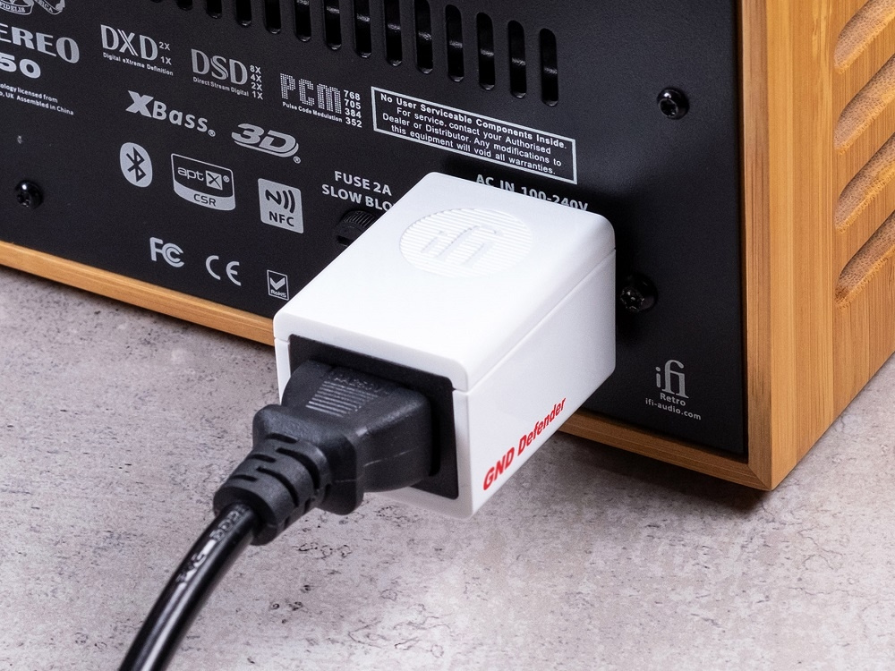 En liten vit enhet ansluten till en ljudapparat, märkta med \