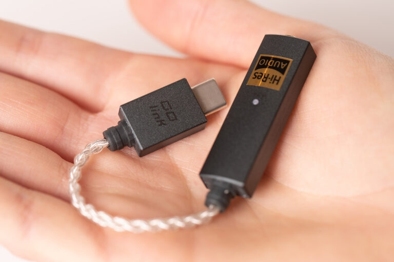 En kompakt hörlursförstärkare i handen med USB-anslutning.