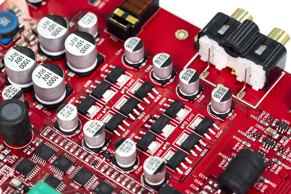 Kretskort med komponenter för hörlursförstärkare, röd nyans.