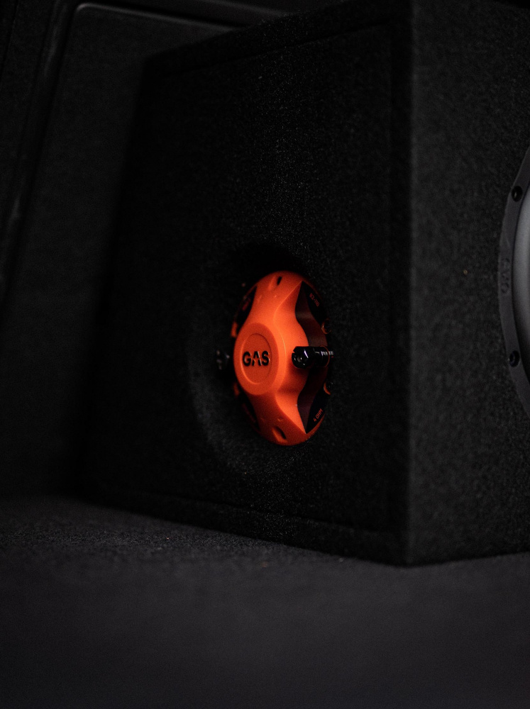 En svart baslåda med en orange högtalare.