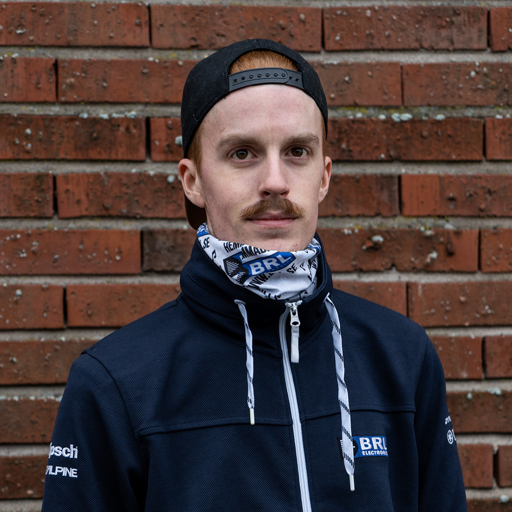 Man bär en tubhalsduk med vit, svart och blå design. Städig outfit.