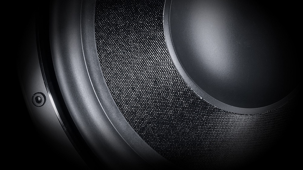 Svart subwoofer med en rund högtalare och texturerad yta.